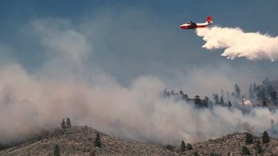 air tanker sprays water on hillside fire