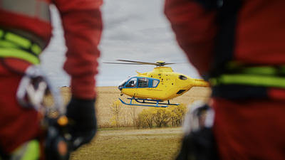 Image of the back of a medical team looking towards a distant helicopter