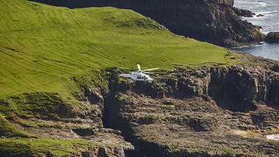 Helicopter flying over cliffs leading to the sea