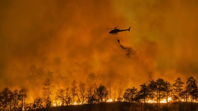 Fire fighting helicopter carry water bucket to extinguish the forest fire