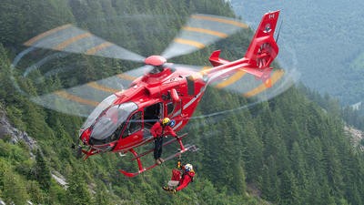 Paramedic hoisting out of red helicopter