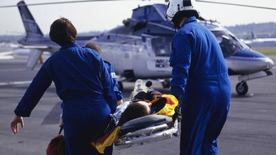 Paramedics bringing patient on stretcher to helicopter
