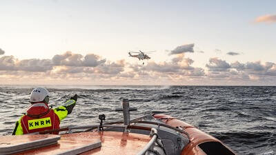 Coast guard pointing at helicopter flying over sea