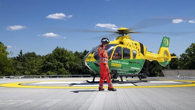 Helicopter pilot on landing deck doing thumbs up as helicopter is about to take off