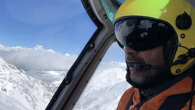 Pilot with a helmet above a snowy mountain 