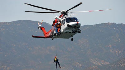 Helciopter flying with SAR paramedic hoisted out of it