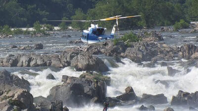 Helicopter flying over rocky water