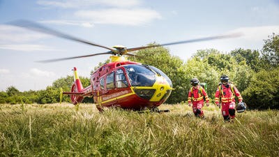 Paramedics walking through field the=at helicopter is parked on
