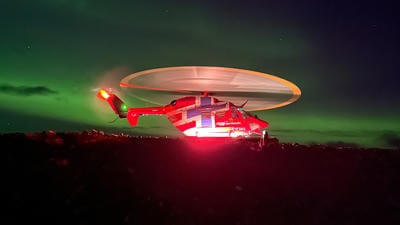 Red Norway helicopter against Northern light backdrop