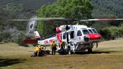 Cal fire helicopter with crew getting ready beside it