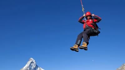 Rescue worker hoisted, mid-air