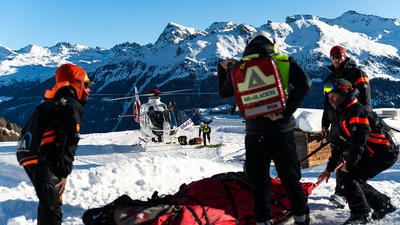 Helicopter parked on snowy mountain with medical team helping casualty