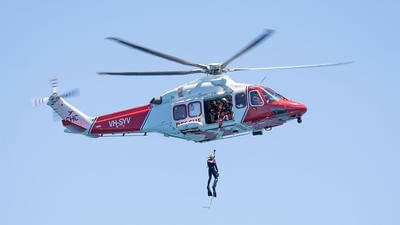 Helicopter flying with person hoisted out
