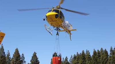 Yellow helicopter carrying water