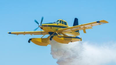Yellow fixed wing firefighting plane dropping fire retardant
