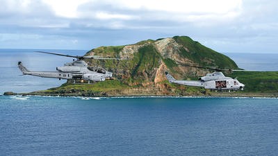 2 helicopters flying over sea