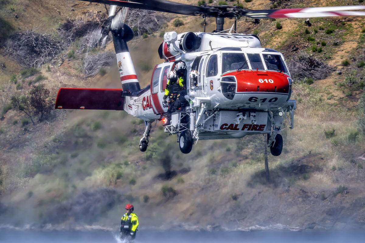 Firefighter jumping into water from helicopter