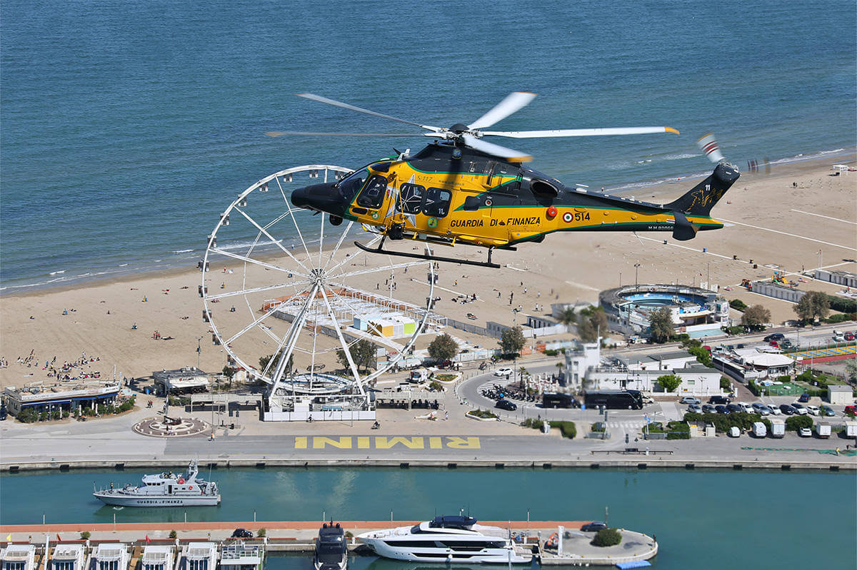 Yellow helicopter flying above sea and harbour