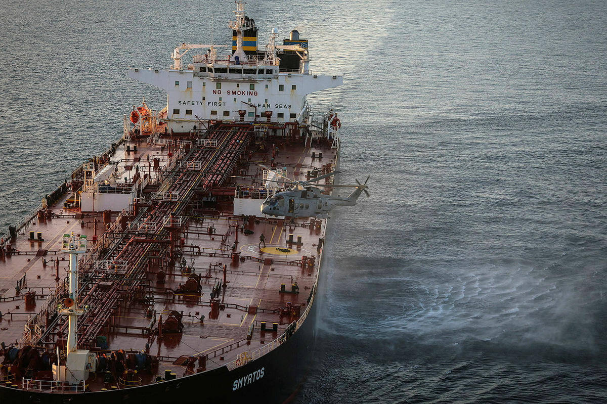 Military helicopter flying next to ship
