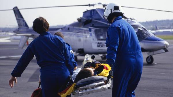 A nurse and pilot carry a patient to a helicopter