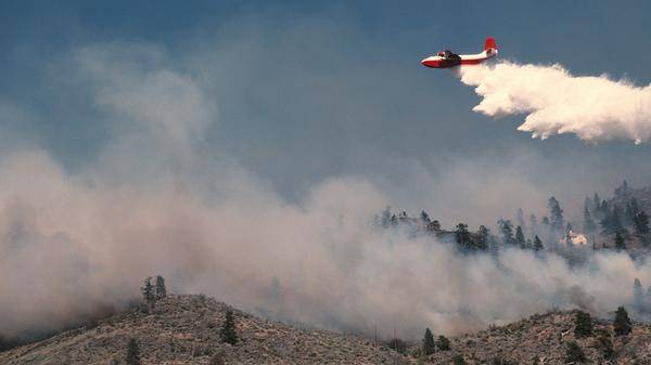 air tanker sprays water on hillside fire
