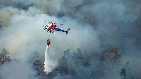 Helicopter putting out fire in field with fire retardant