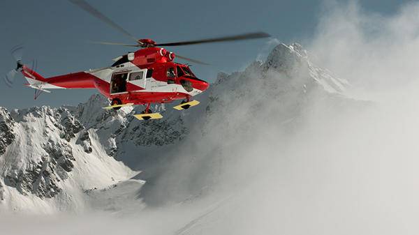 Red helicopter landing in snow