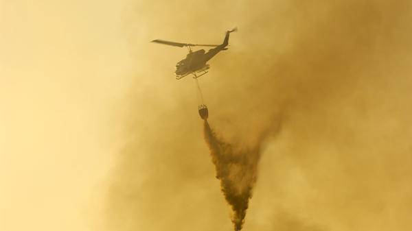 Helicopter dropping fire retardant against yellow background
