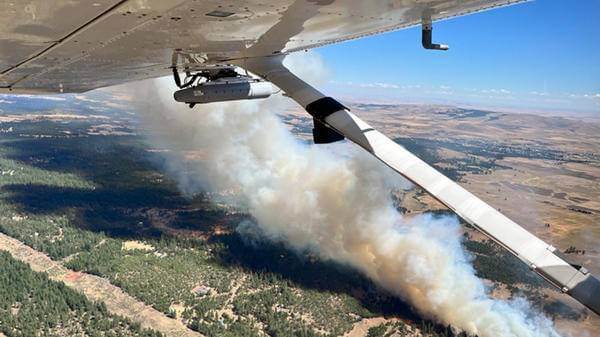 Plane dropping fire retardant on trees