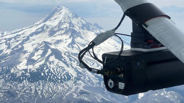 Device on bottom of plane overlooking snowy mountains