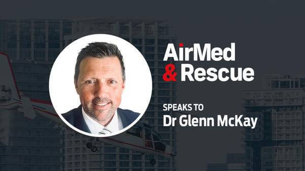 Dr Glenn McKay headshot in front of helicopter