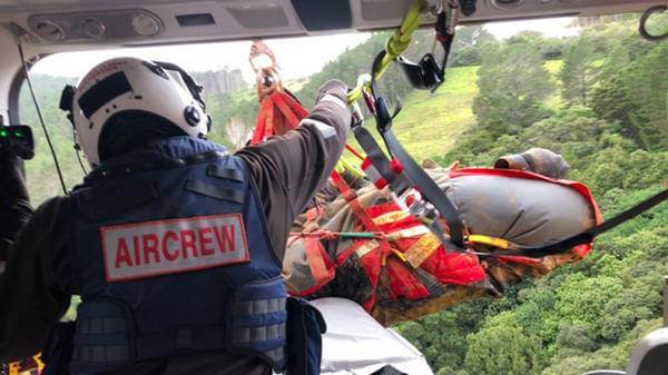 Aircrew bringing suspended patient into moving helicopter