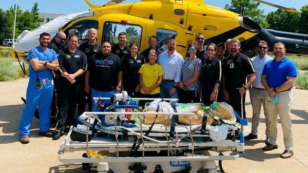 Large group of PHI and MCH staff in front of air ambulance helicopter