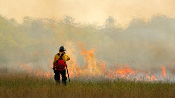 Image of firefighter with wildfire in background