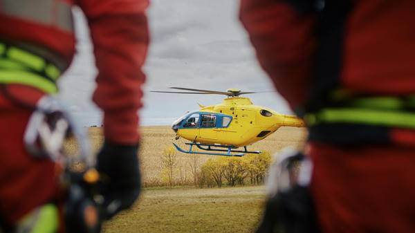 Image of the back of a medical team looking towards a distant helicopter