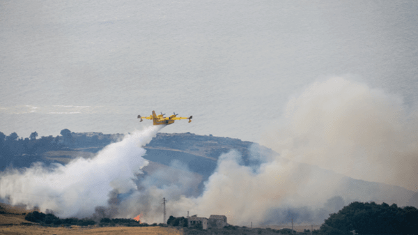 Plane flying over hill dropping fire retardant