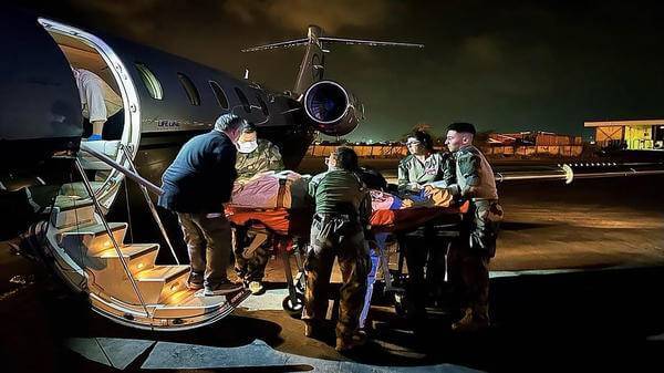 Paramedics wheeling patient onto plane