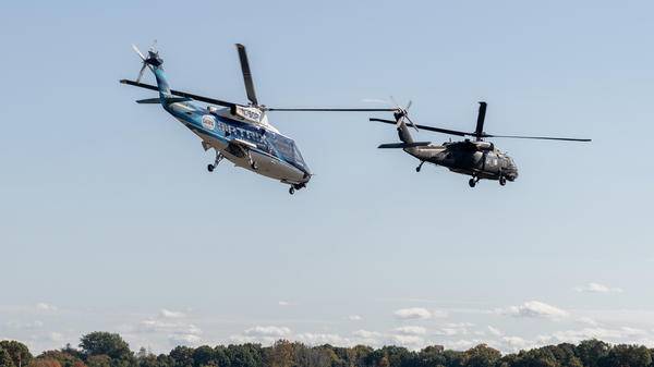 2 helicopters flying in sky