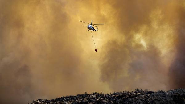 Aerial firefighting helicopter dropping fire retardant on wildfire