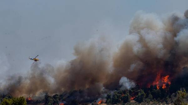 Aerial firefighting helicopter dropping fire retardant on wildfire