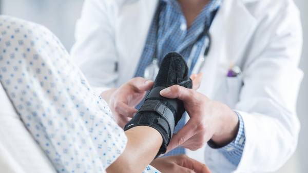 Doctor helping patient with broken arm