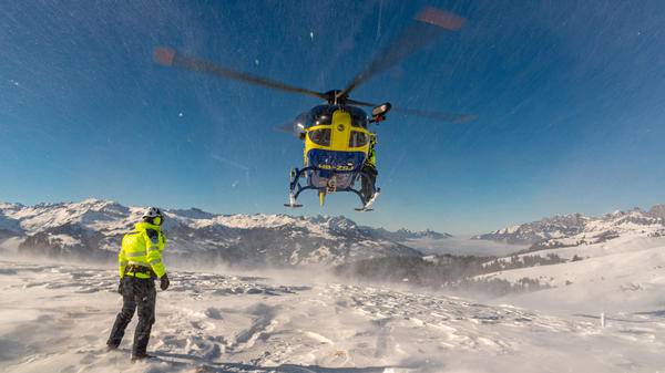 Yellow helicopter flying over snowy mountain