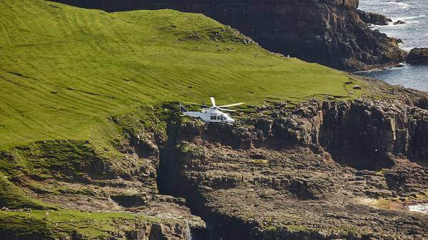 Helicopter flying over cliffs leading to the sea