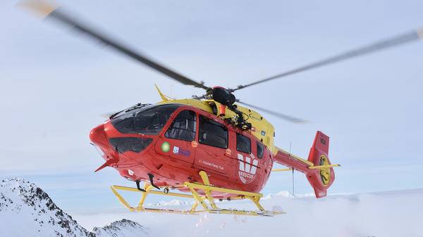 Red rescue helicopter in snowy mountains