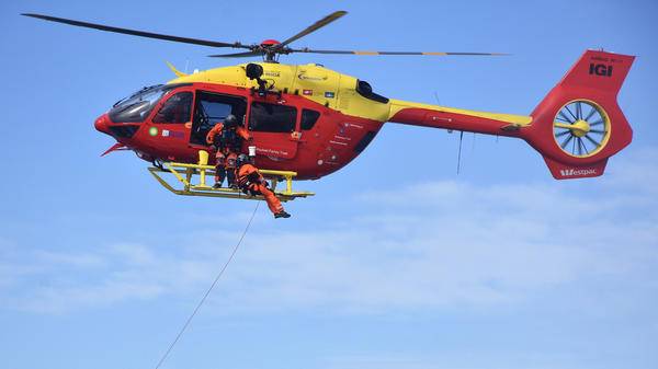 Rescue worker hoisting out of red rescue helicopter