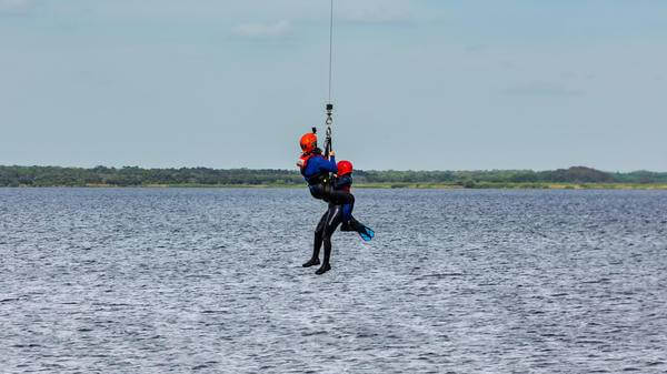 Rescue swimmers being hoisted into water
