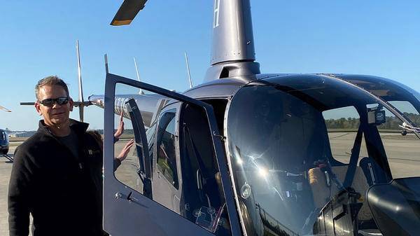 Chris Bauer posing next to helicopter