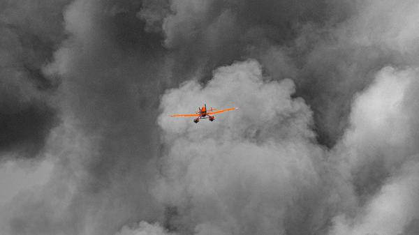 Yellow plane flying in distance with black smoke behind