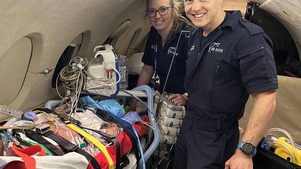 Ulrich posing with patient and colleague inside of air ambulance