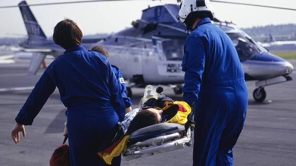 Paramedics bringing patient on stretcher to helicopter